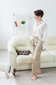 Young attractive woman dressed in beautiful colorful pajama posing as a model in her living room. Comfortable sleepwear, home relaxation and female fashion concept