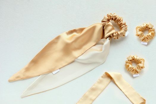 golden silk scrunchy flat lay on white. Hairdressing tools and accessories. luxury ladyes Hair Scrunchie, Elastic Hair Band, Bobble Sport Scrunchie Hairband. hair scarf fixed on the scrunchie