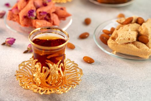 Assortment of Turkish delights with glass of tea on gray background, close up
