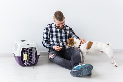 Dog carrying bags and pets owner concept - Attractive cheerful male in plaid shirt holds favourite pet. Happy bearded man with his jack russell terrier.