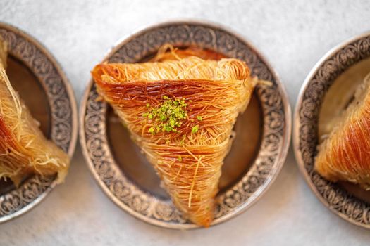 Turkish baklava on oriental metal plate on white table, close up