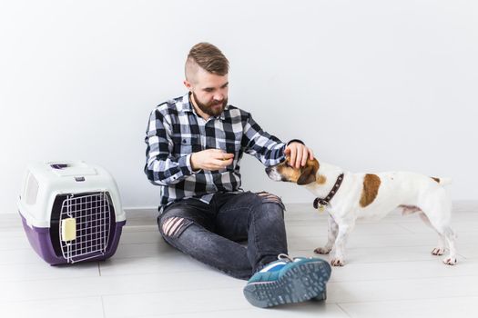 Dog carrying bags and pets owner concept - Attractive cheerful male in plaid shirt holds favourite pet. Happy bearded man with his jack russell terrier.