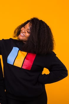 Young beautiful african american girl with an afro hairstyle. Portrait on yellow background