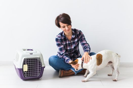 Dog carrying bags and pets owner concept - Attractive cheerful female in plaid shirt holds favourite pet. Happy woman with her jack russell terrier.