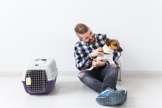 Dog carrying bags and pets owner concept - Attractive cheerful male in plaid shirt holds favourite pet. Happy bearded man with his jack russell terrier.