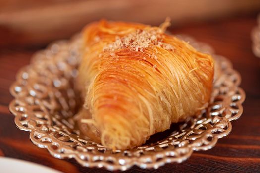 Turkish sweets on small plate on brown wooden background, close up