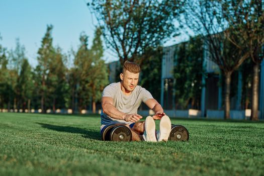 athletic man with dumbbells in the park exercise motivation. High quality photo