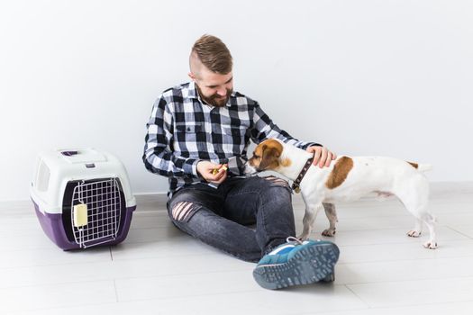 Dog carrying bags and pets owner concept - Attractive cheerful male in plaid shirt holds favourite pet. Happy bearded man with his jack russell terrier.