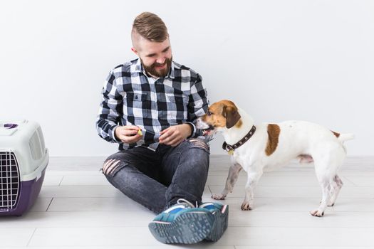 Dog carrying bags and pets owner concept - Attractive cheerful male in plaid shirt holds favourite pet. Happy bearded man with his jack russell terrier.