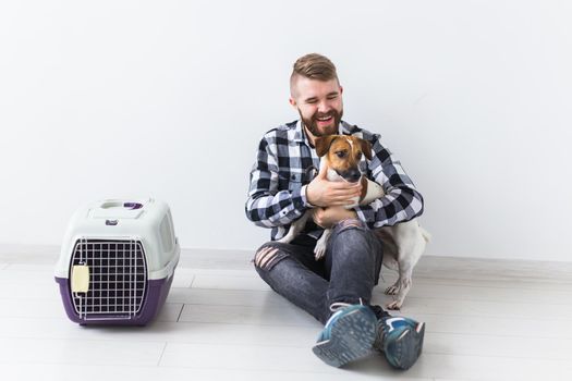 Dog carrying bags and pets owner concept - Attractive cheerful male in plaid shirt holds favourite pet. Happy bearded man with his jack russell terrier.