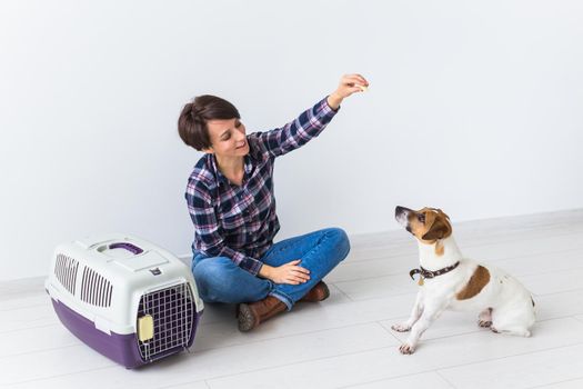 Dog carrying bags and pets owner concept - Attractive cheerful female in plaid shirt holds favourite pet. Happy woman with her jack russell terrier.