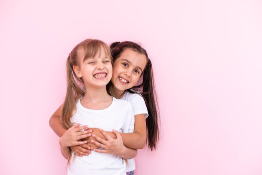 Two little girls - best friends, isolated over on a pink background
