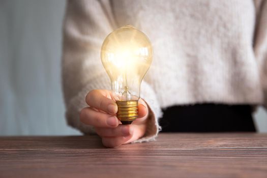 Female hand holding a shining light bulb, Great idea, innovation and inspiration, business concept background modern retro design