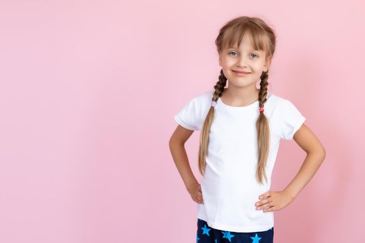 Beautiful little blonde girl with long hair in white T-shirt smiling on a pink background