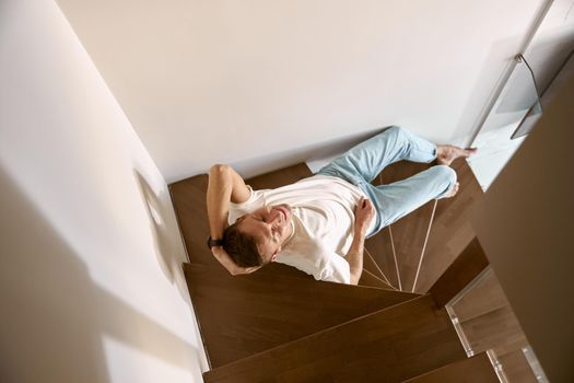 Relaxing happy caucasian man on the minimalistic stairs in modern light apartment