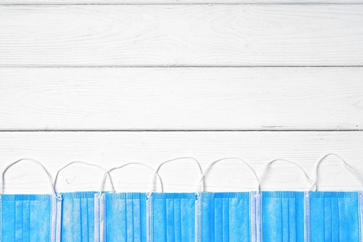 Blue medical face masks on white wooden background
