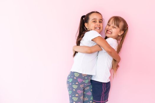 Two little girls - best friends, isolated over on a pink background