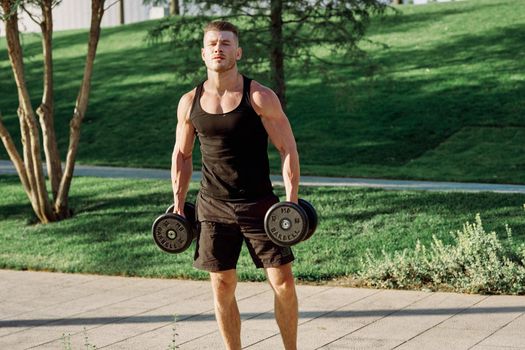 athletic man with dumbbells workout outdoors motivation. High quality photo