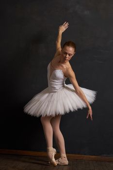 woman ballerina in a white tutu dance posing performance dark background. High quality photo