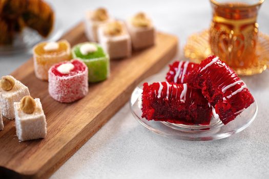 Various Turkish sweets and cup of tea on white textured background, close up