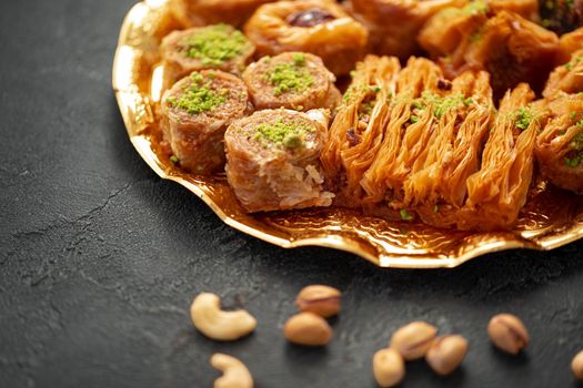 Delicious baklava dessert in oriental setting on black background, close up