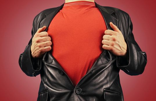 Unrecognizable man opens suit showing red t-shirt on a red background