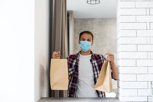 Delivery man holding paper bag with food, food delivery man in protective mask