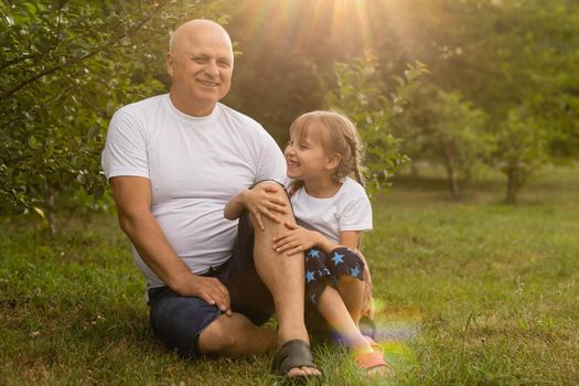 Portrait Of Grandfather With Granddaughter Relaxing Together in the garden