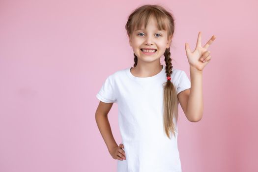 Beautiful little blonde girl with long hair in white T-shirt smiling on a pink background