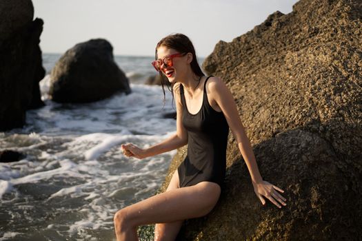 woman in black swimsuit rocks posing oceans. High quality photo