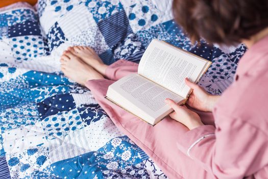 Happy woman wears pajama and relaxing at home and reading a book. Stay home. Quarantine pandemic coronavirus.