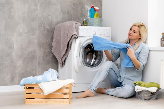 A young housewife with washing machine and clothes. Washing day.