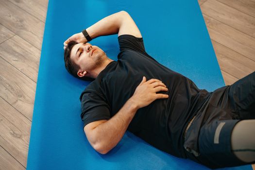 Young muscular caucasian handsome man doing abs exercises on a mat