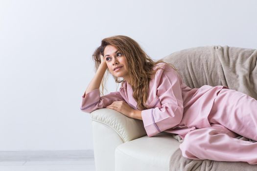 Young attractive woman dressed in beautiful colorful pajama posing as a model in her living room. Comfortable sleepwear, home relaxation and female fashion concept