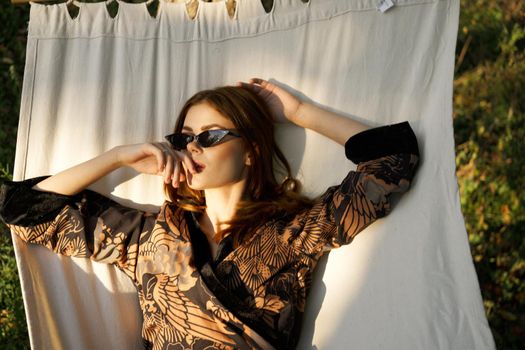 pretty woman lies in a hammock wearing sunglasses summer lifestyle leisure. High quality photo
