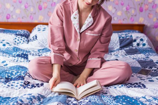 Happy woman wears pajama and relaxing at home and reading a book. Stay home. Quarantine pandemic coronavirus.