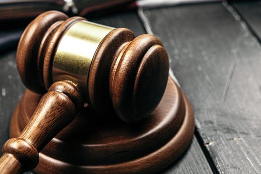 Judge's gavel on wooden table in dark. Close up.