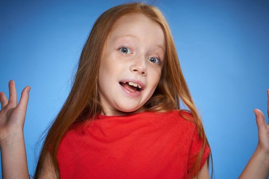 cute red-haired girl in red t-shirt emotions blue background. High quality photo