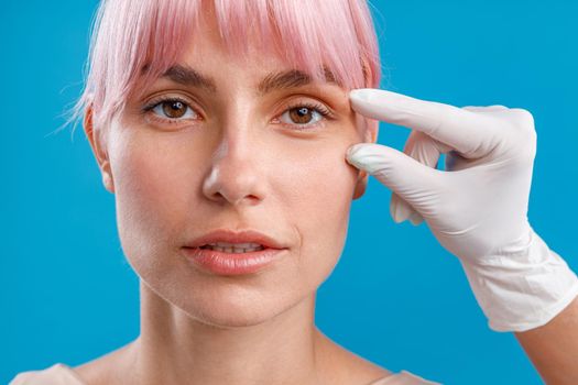 Hand of beautician touching female face, examining it before giving botox injection. Beauty concept