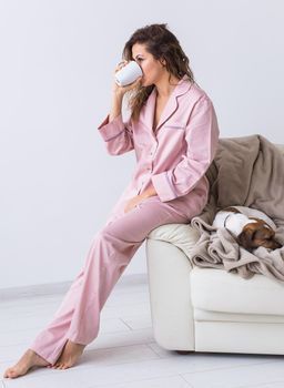 Young attractive woman dressed in beautiful colorful pajama posing as a model in her living room. Comfortable sleepwear, home relaxation and female fashion concept