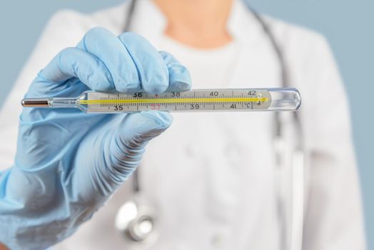 Unrecognizable nurse holds thermometer, focus on thermometer, face is not visible