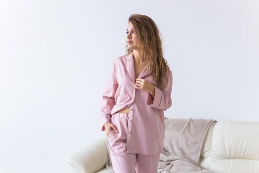 Young attractive woman dressed in beautiful colorful pajama posing as a model in her living room. Comfortable sleepwear, home relaxation and female fashion concept