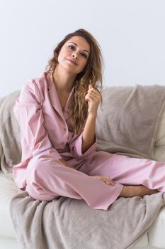 Young attractive woman dressed in beautiful colorful pajama posing as a model in her living room. Comfortable sleepwear, home relaxation and female fashion concept