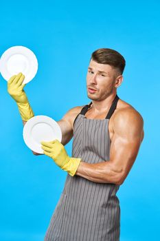 Cheerful man in aprons washing dishes housework blue background. High quality photo