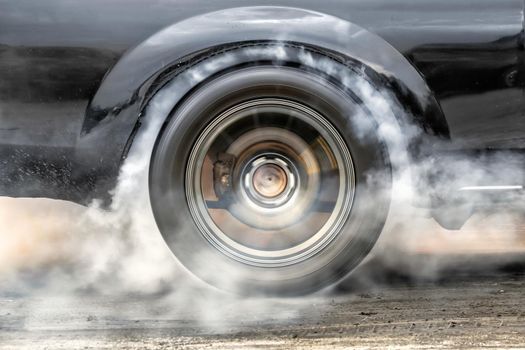 Drag racing car burns rubber off its tires in preparation for the race