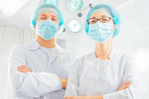 Two surgeons doctors in a mask and a cap in a hospital
