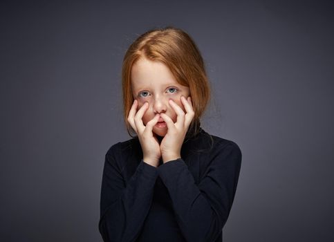 red-haired girl with freckles on her face in a black sweater posing. High quality photo