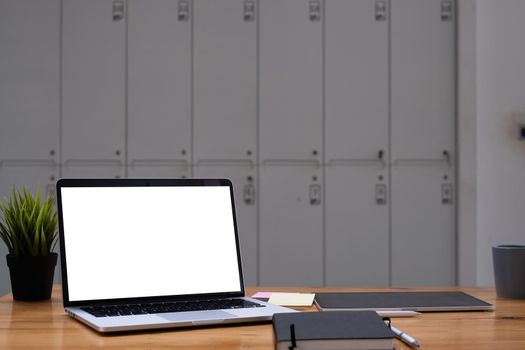 Image of Mock up laptop computer on wooden desk in office. Blank screen for your advertising