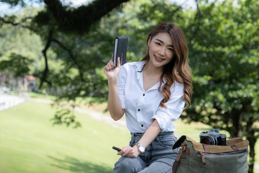 Image of pleased positive woman sitting outdoors in park