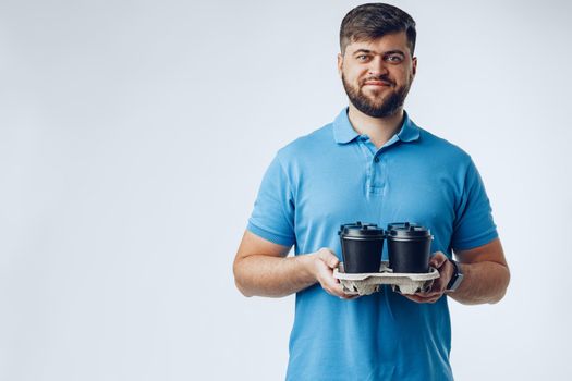 Man coffee shop worker giving takeaway cups of coffee on light grey background